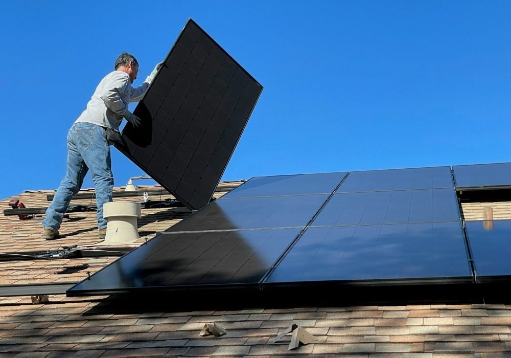 man in white dress shirt and blue denim jeans sitting on white and black solar panel